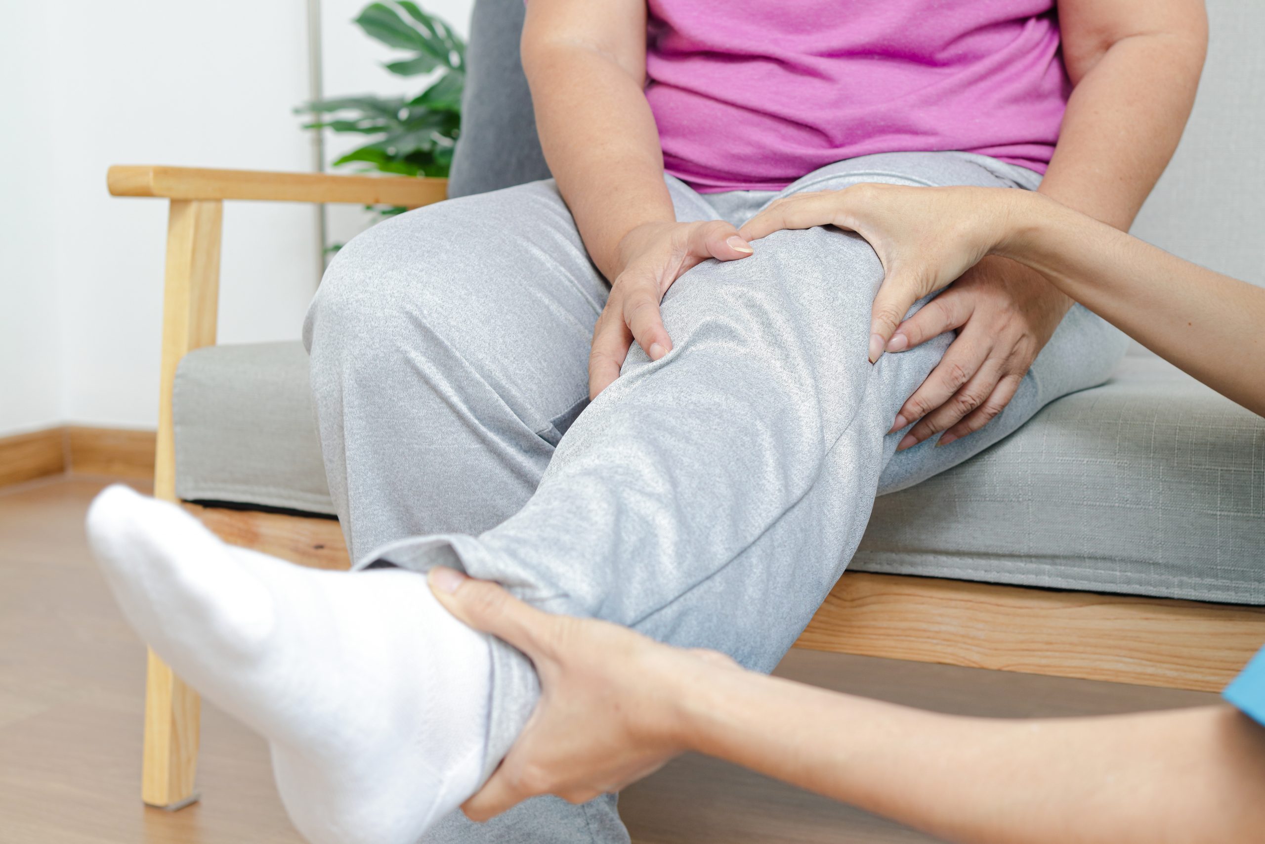 Asian female doctor doing physical therapy for elderly people with leg pain.