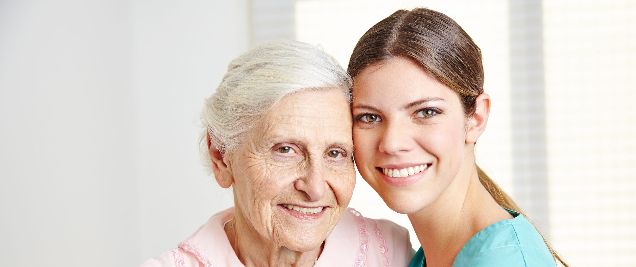 Caregiver embracing happy senior woman